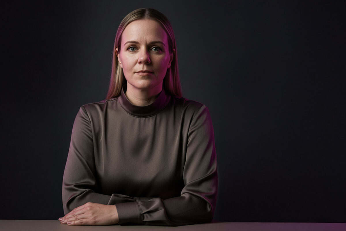 Porträt einer Frau in ruhiger, seriöser Pose vor dunklem Hintergrund, mit zurückhaltender Mimik und subtiler Magenta-Lichtakzentuierung – aufgenommen für einen Artikel über die Persönlichkeit hinter tsbw. Brand & Airdesign.