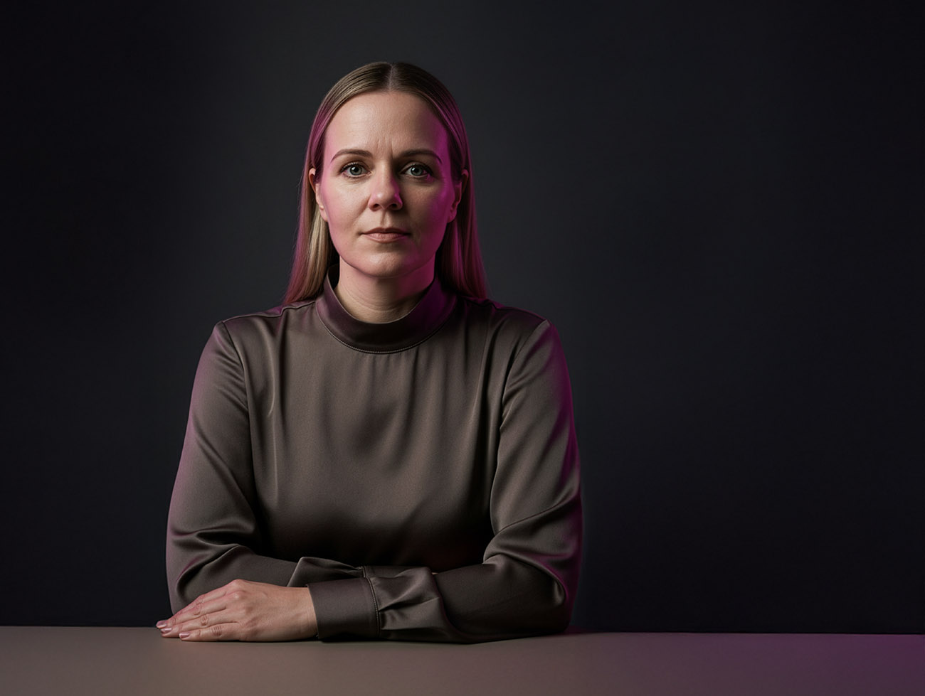 Porträt einer Frau in ruhiger, seriöser Pose vor dunklem Hintergrund, mit zurückhaltender Mimik und subtiler Magenta-Lichtakzentuierung – aufgenommen für einen Artikel über die Persönlichkeit hinter tsbw. Brand & Airdesign.